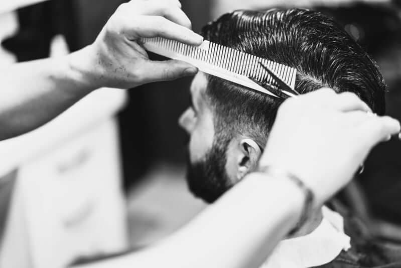 Barbier knipt een herenkapsel met kam en schaar