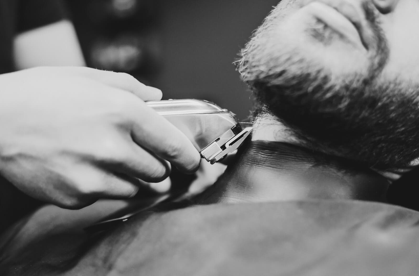 Barbier werkt de nek en de baardlijn bij met een tondeuse